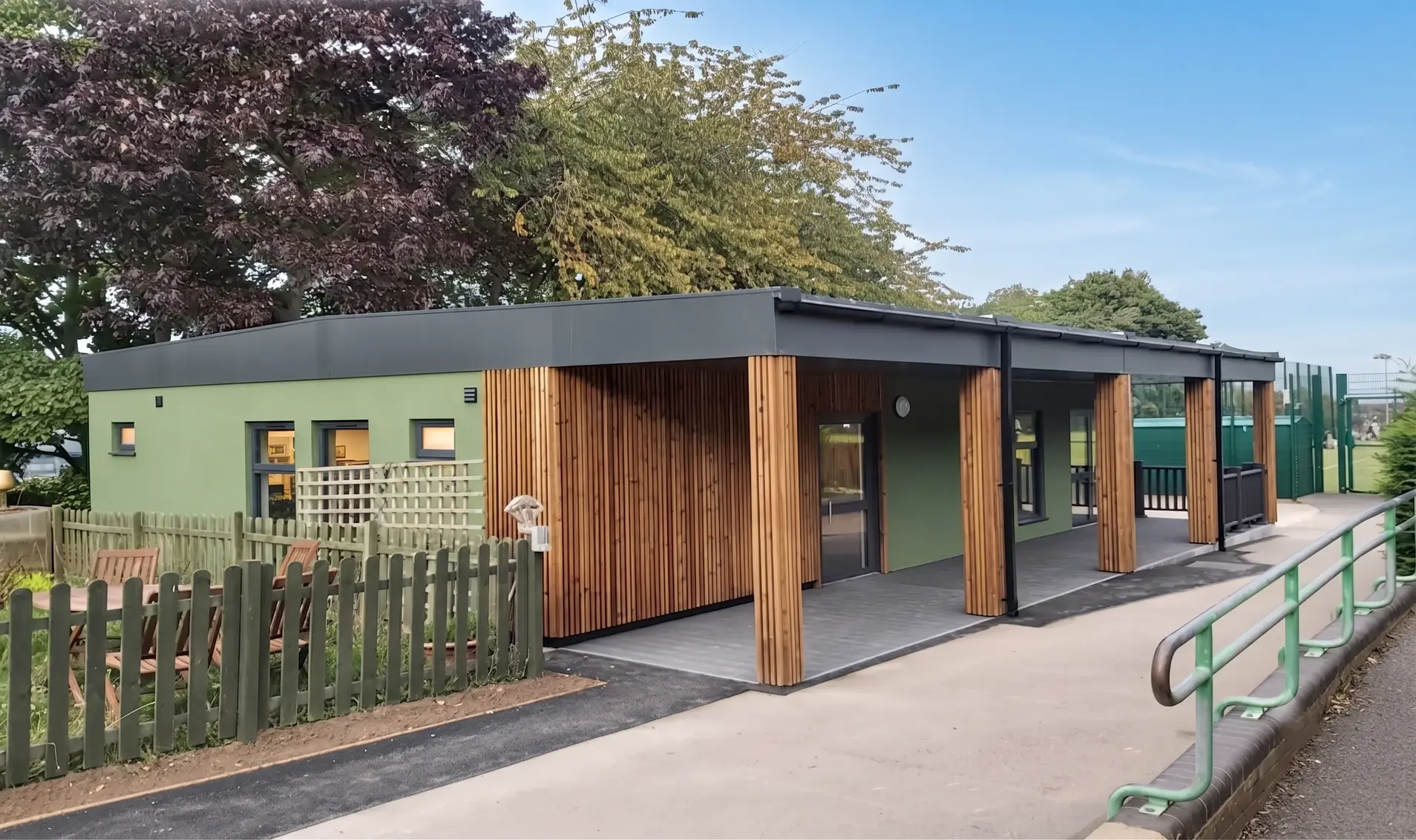 Prefabricated temporary modular classroom in Green and Wood Cladding for Extension next to all weather sports ground